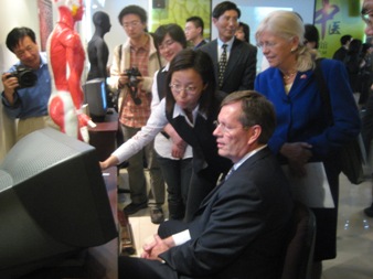 U.S. Secretary of Health and Human Services (HHS) Michael O. Leavitt (right) and Josephine Briggs, M.D., the Director of the National Center for Complementary and Alternative Medicine of the HHS National Institutes of Health (left), receive a lesson in acupunture techniques from a student at the Shanghai University of Traditional Chinese Medicine, in Shanghai, China. (Photo Credit: Bill Steiger, HHS)